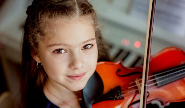 Home lesson for a girl playing the violin. The idea of activities for children during quarantine. Music concept